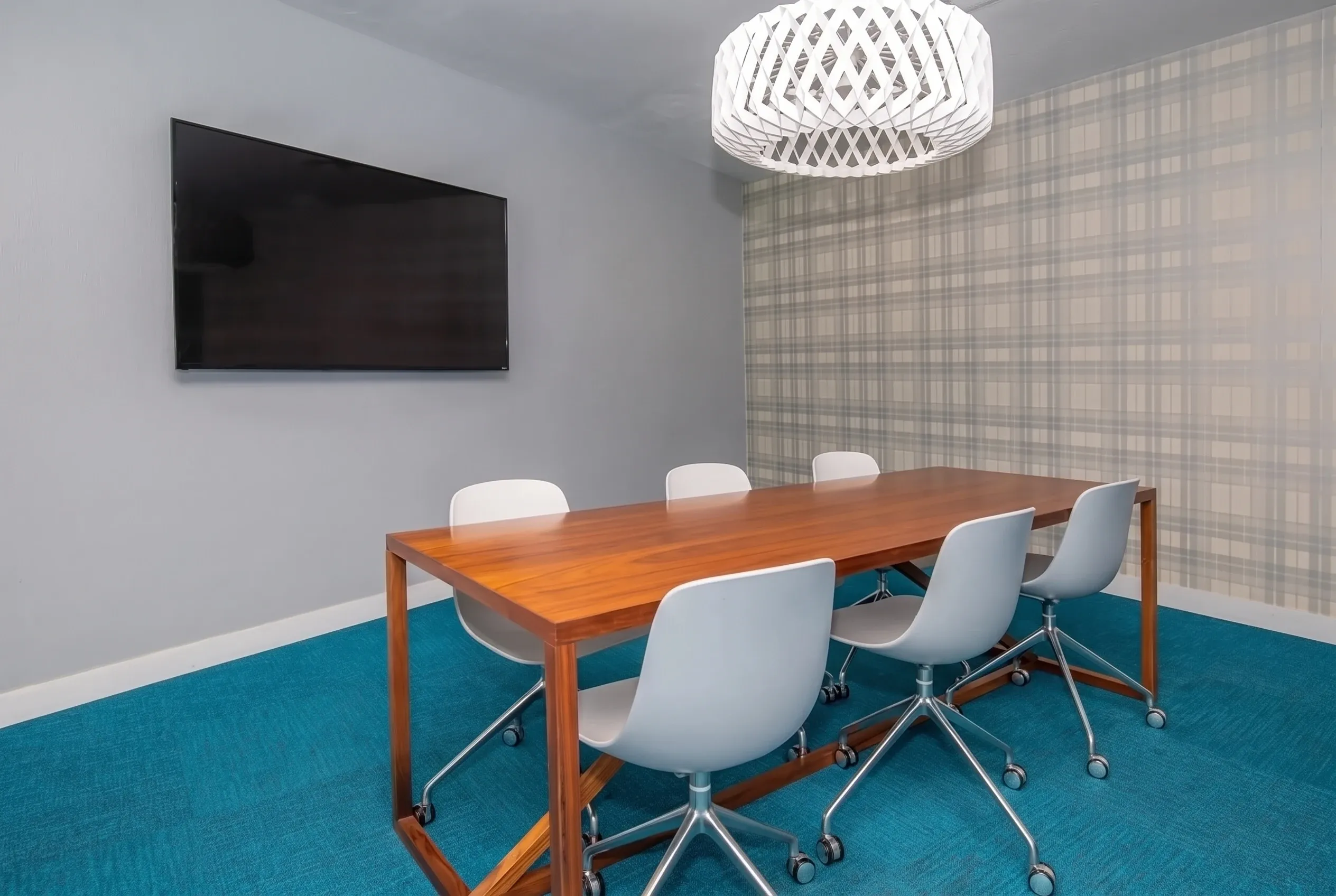 Conference room, wood table, white modern chairs with casters, turquoise carpet, white pendant light