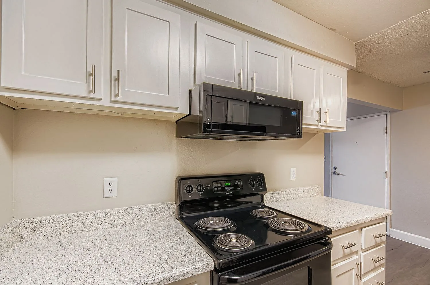 Kitchen, white shaker cabinetry, speckled quartz countertops, black electric range, black microwave