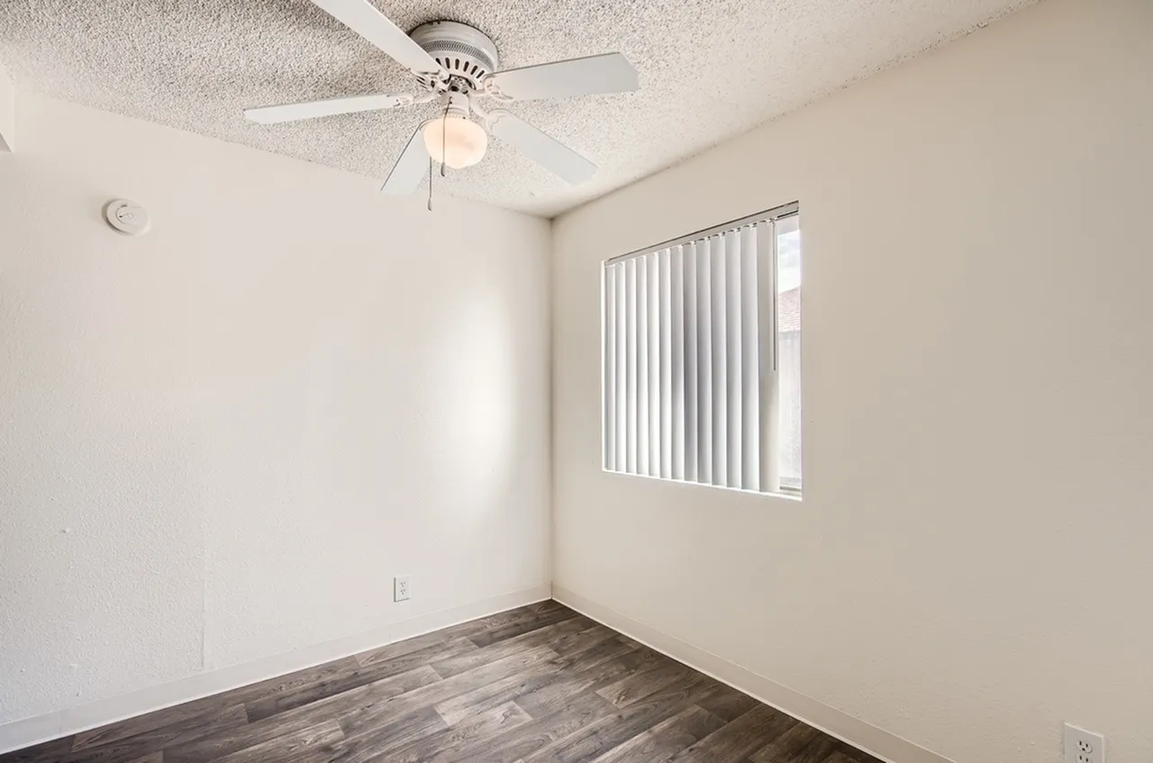 Bedroom, wood-style plank flooring, ceiling fan with light, vertical blinds, neutral walls