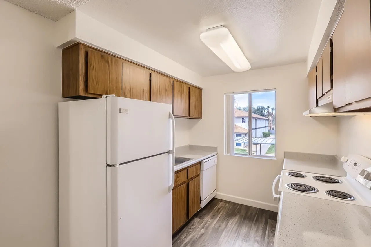 Kitchen, wood cabinetry, white refrigerator, white range, wood-style plank flooring, window
