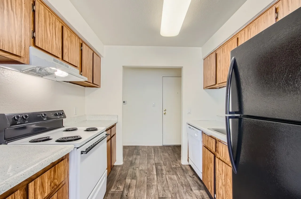 Kitchen, wood cabinetry, white countertops, black electric range, black refrigerator, wood-style plank flooring