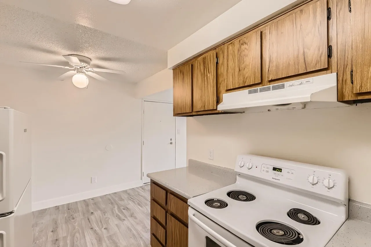 Kitchen, wood cabinetry, white electric range, laminate countertops, wood-style plank flooring, ceiling fan