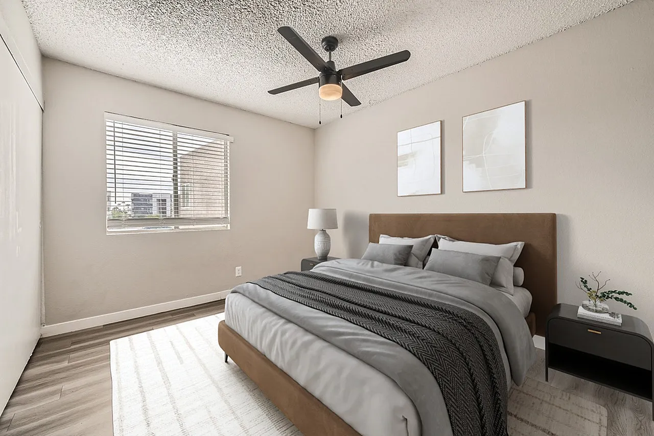 Primary bedroom, wood-style plank flooring, ceiling fan, upholstered headboard, black nightstand