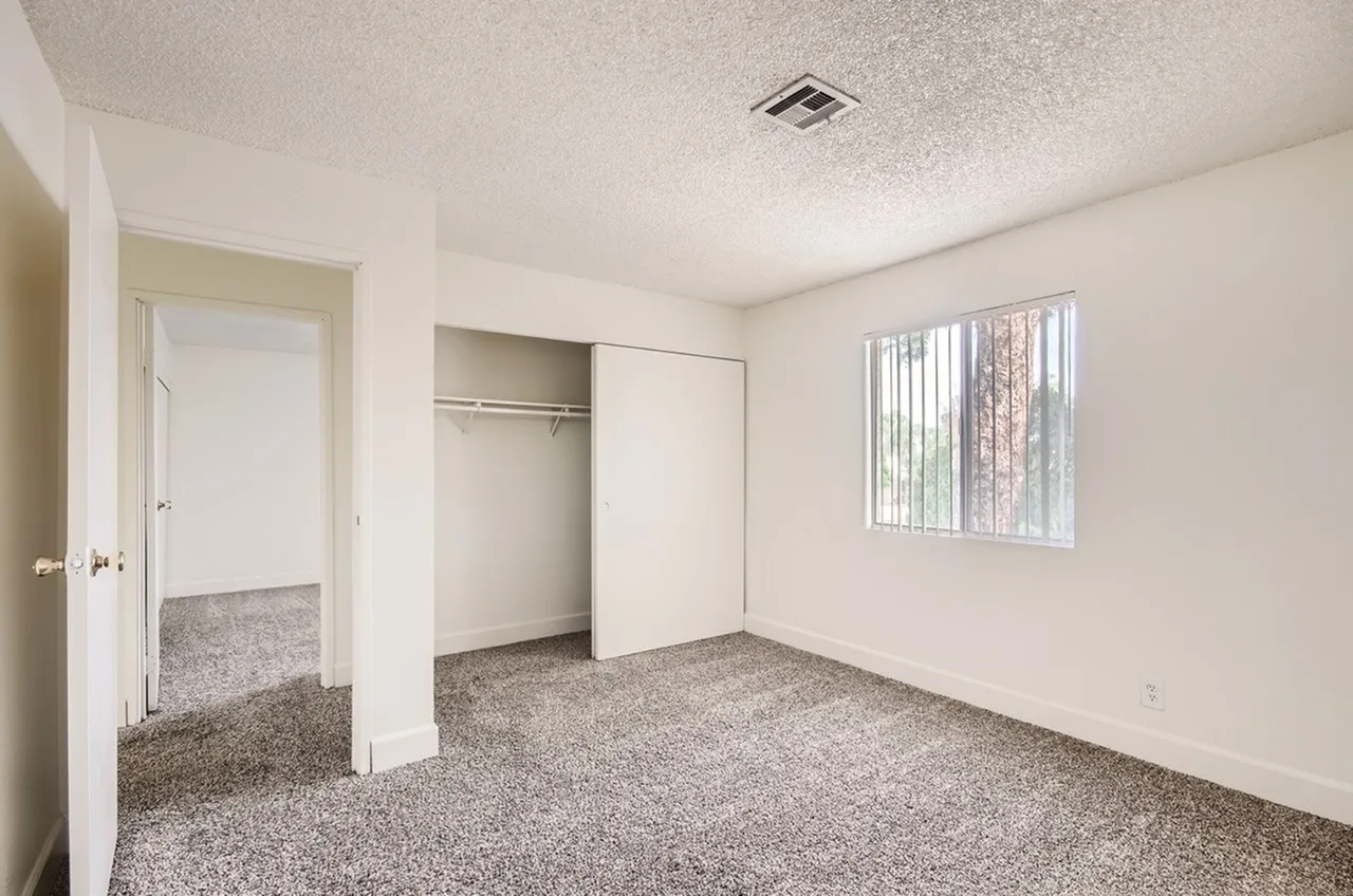 Primary bedroom, gray carpet flooring, walk-in closet, window with blinds