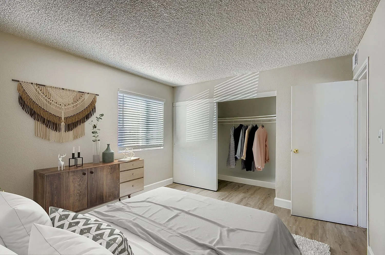 Primary bedroom, wood-style plank flooring, dresser with mirror, walk-in closet