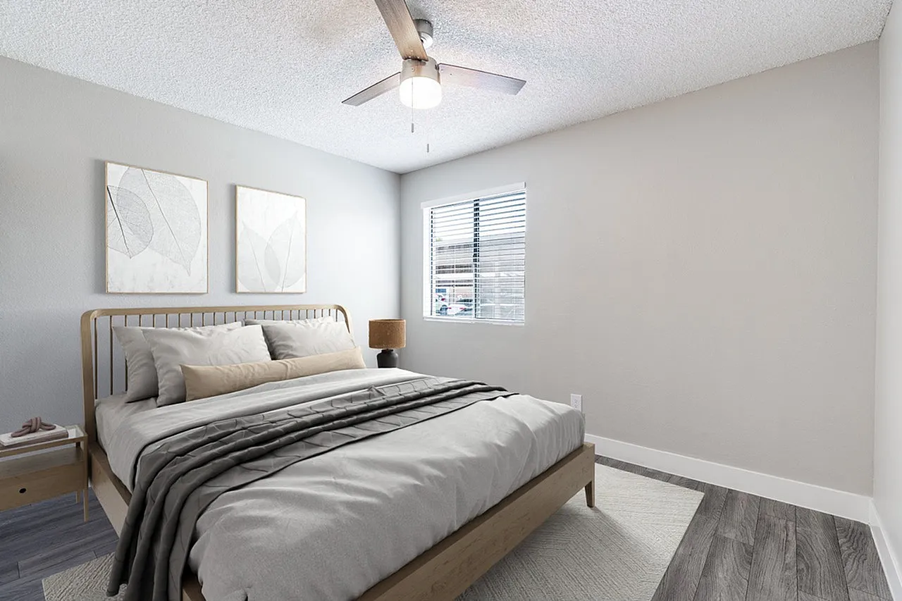 Primary bedroom, wood-style plank flooring, ceiling fan, upholstered headboard, window with shutters