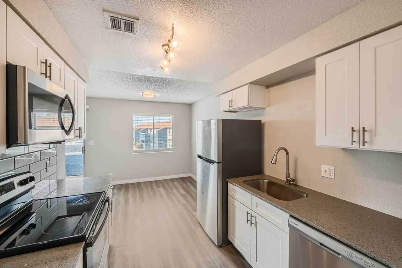 Kitchen, white shaker cabinetry, stainless steel appliances, wood-style plank flooring