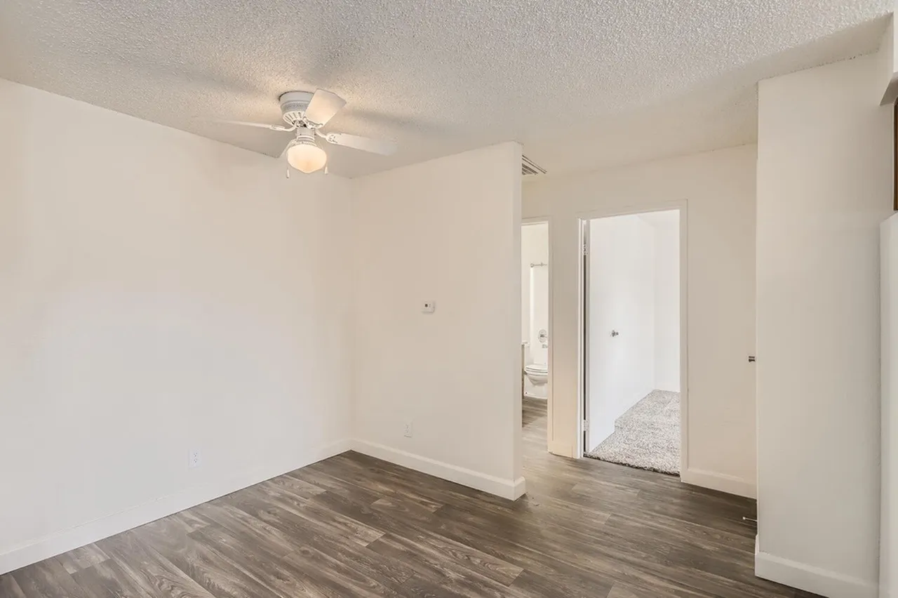 Bedroom, wood-style plank flooring, white walls, ceiling fan, mirrored closet doors