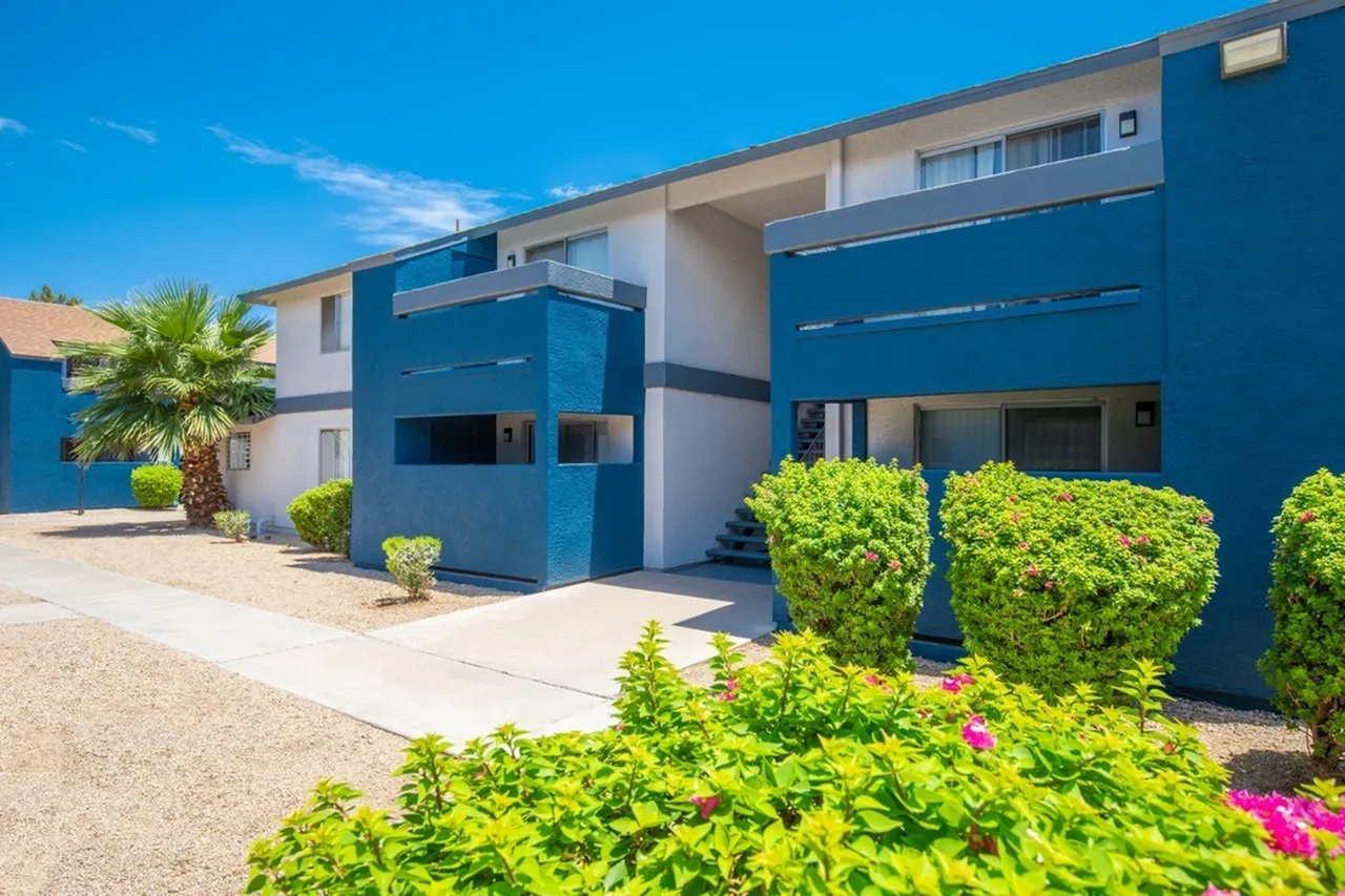 Contemporary building exterior, blue and white facade, modern garage doors, landscaped shrubs with pink flowers