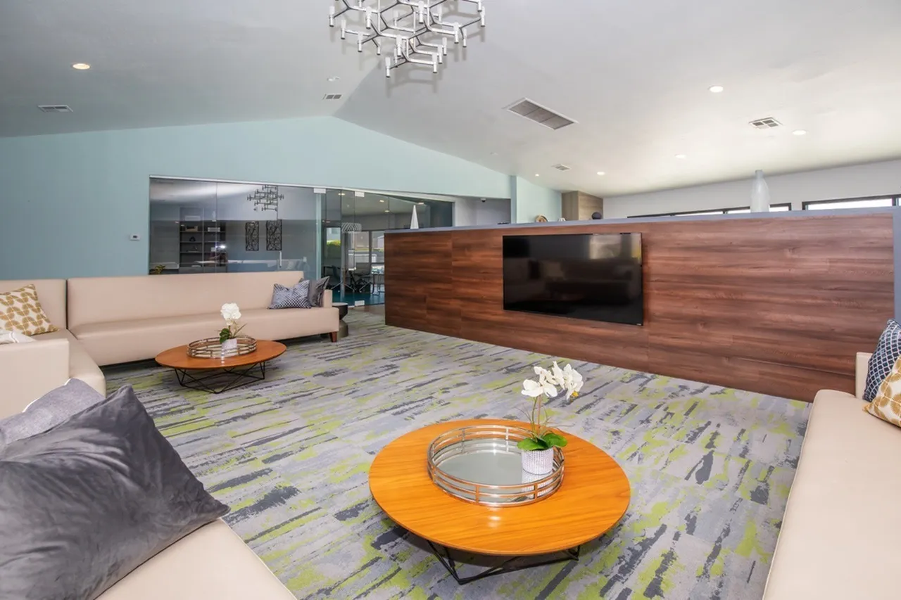 Lounge with cream sofas, patterned area rug, orange side table, wood-style accent wall, TV