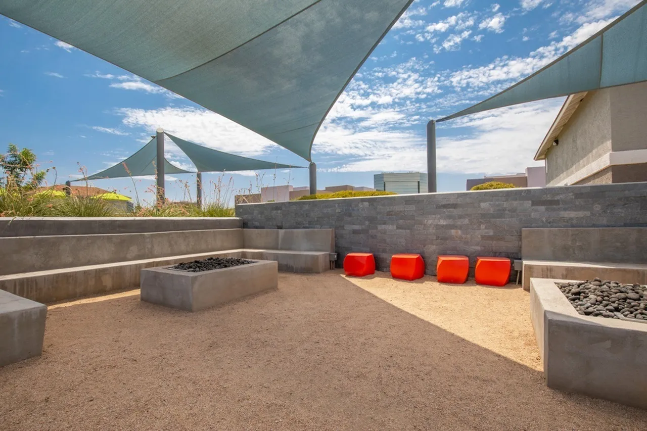 Rooftop terrace, shade structures, concrete planter beds, red seating poufs