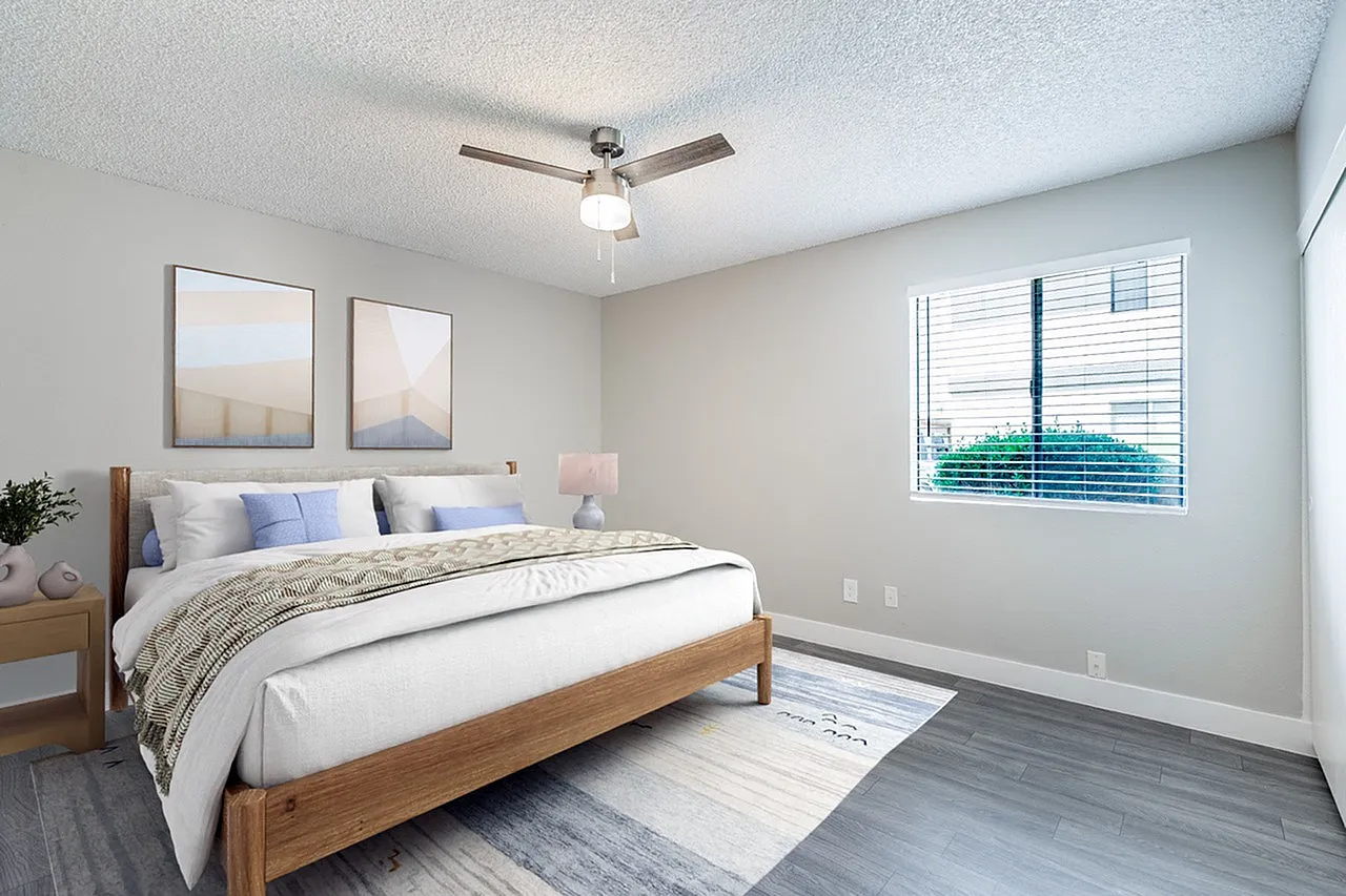 Primary bedroom, wood-style plank flooring, ceiling fan, framed wall art
