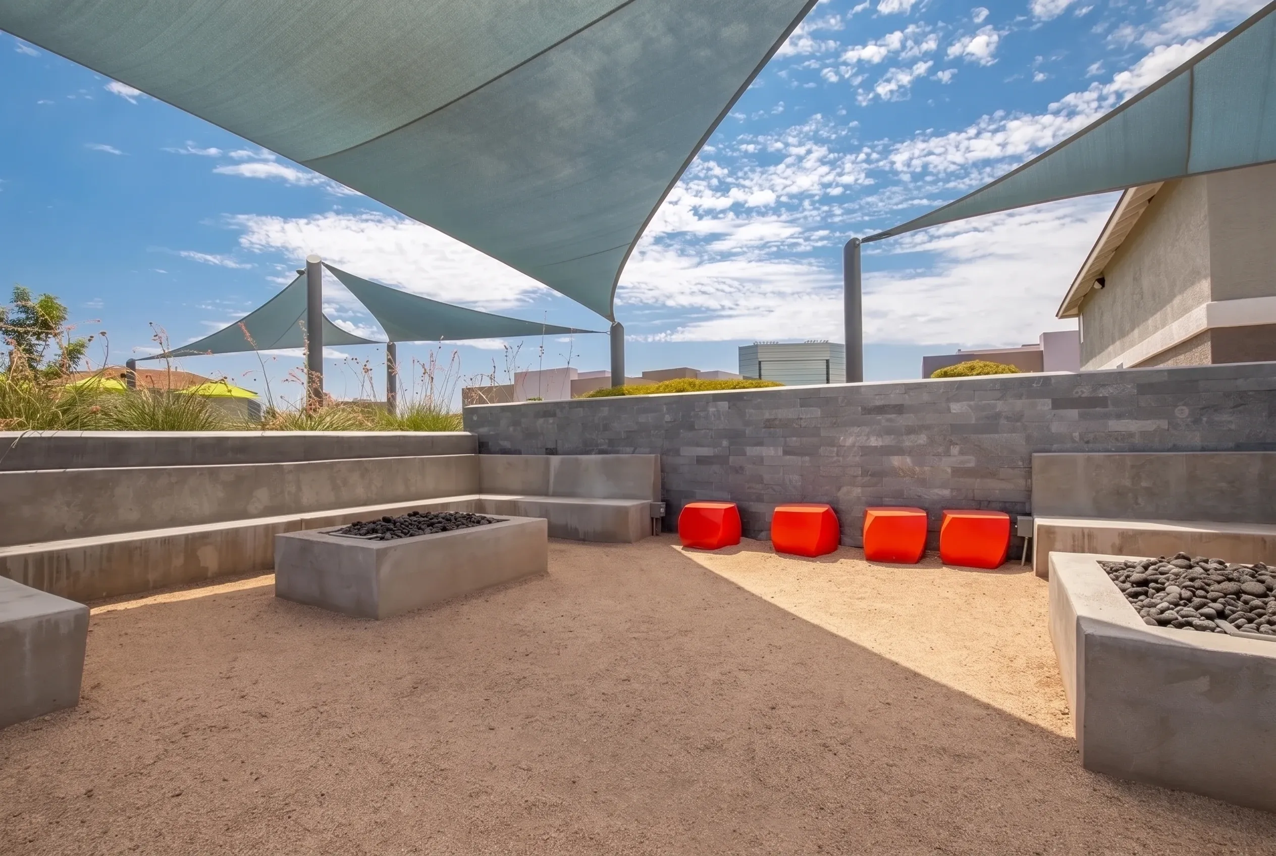 Rooftop terrace, shade structures, concrete planter beds, red seating poufs