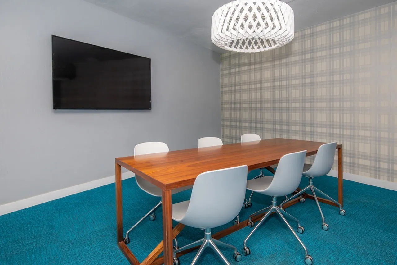 Conference room, wood table, white modern chairs with casters, turquoise carpet, white pendant light