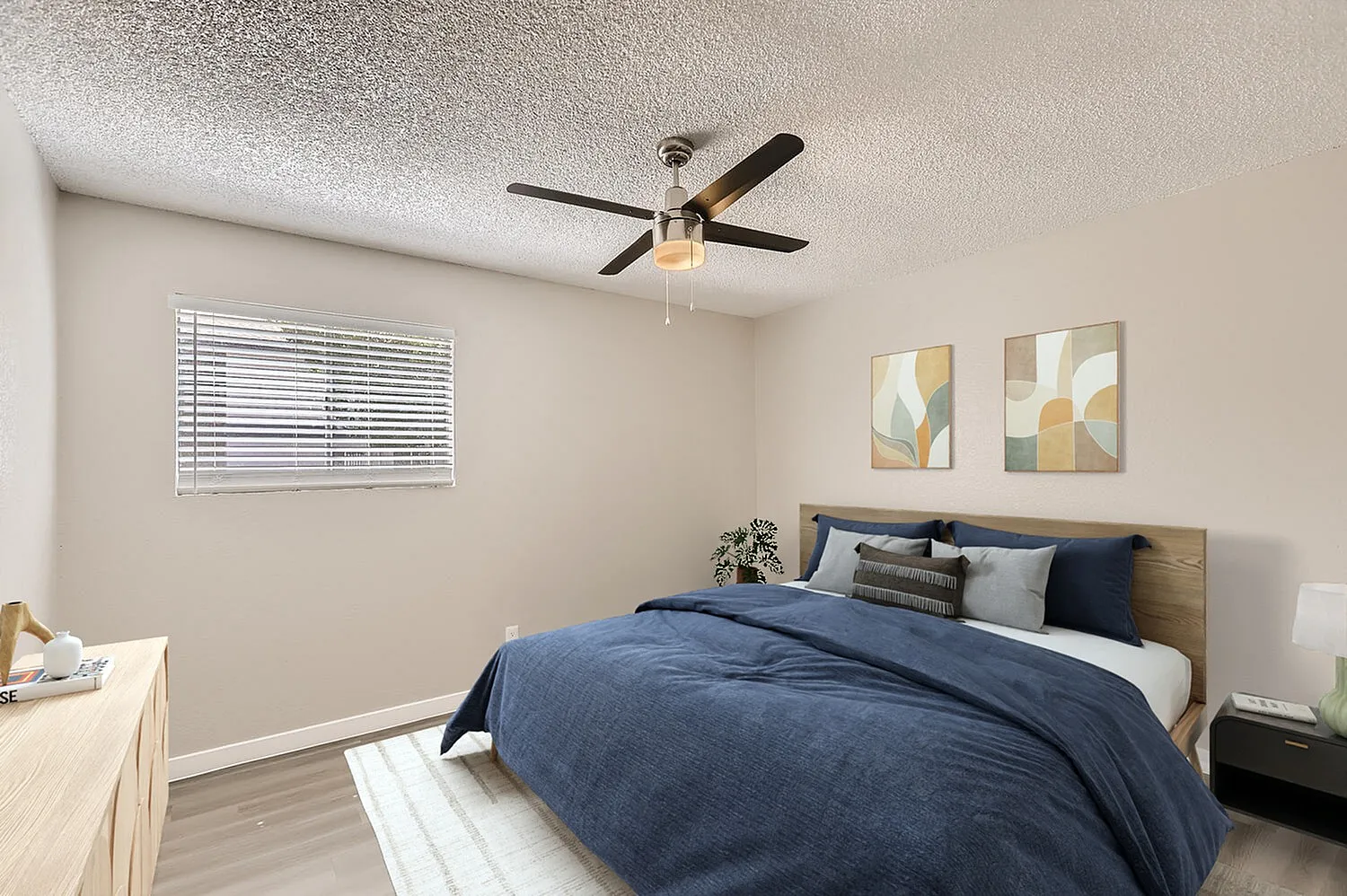 Primary bedroom, wood-style plank flooring, ceiling fan, blue bedding, wood headboard