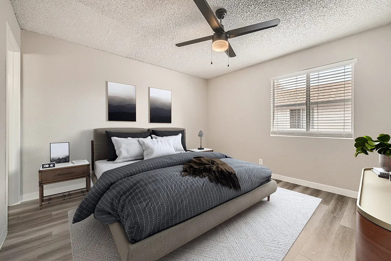 Primary bedroom, gray upholstered bed, wood-style plank flooring, ceiling fan, windows