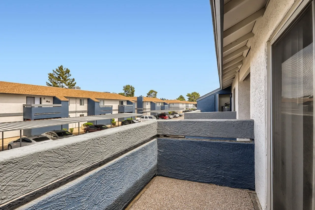Balcony, textured railing, courtyard view, clear sky, landscaping