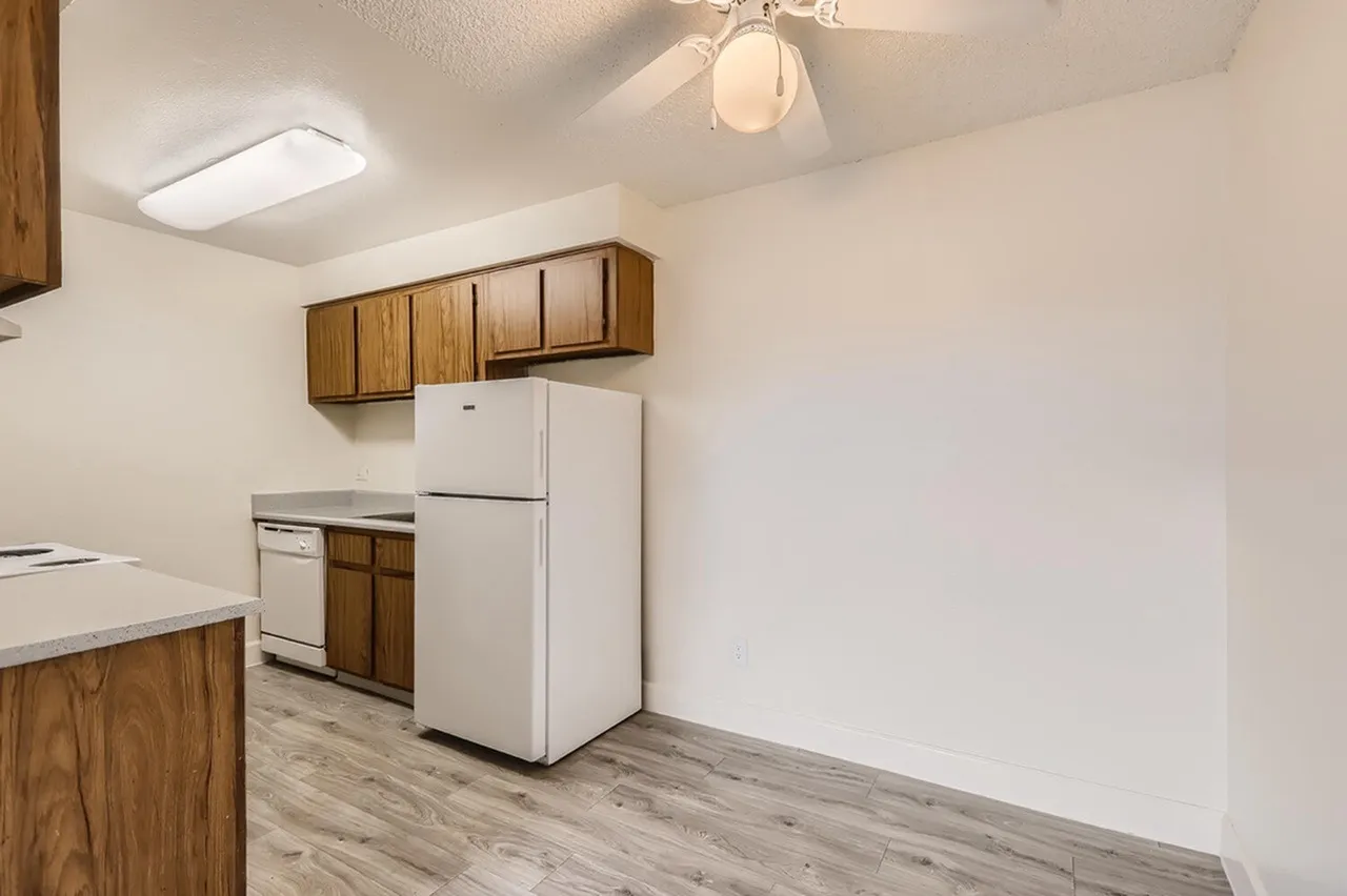 Kitchen, wood cabinetry, white appliances, wood-style plank flooring, ceiling fixture