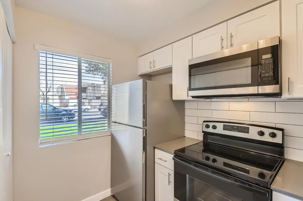 Kitchen, white shaker cabinetry, subway tile backsplash, stainless steel appliances, sliding glass window with exterior view