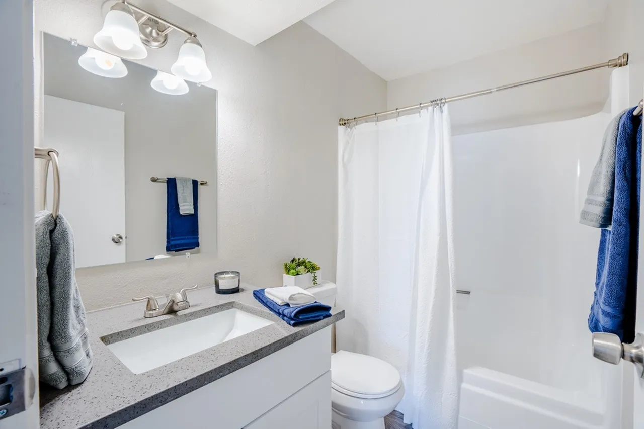 Primary bathroom, gray quartz countertops, white cabinetry, vessel sink, mirror with lighting