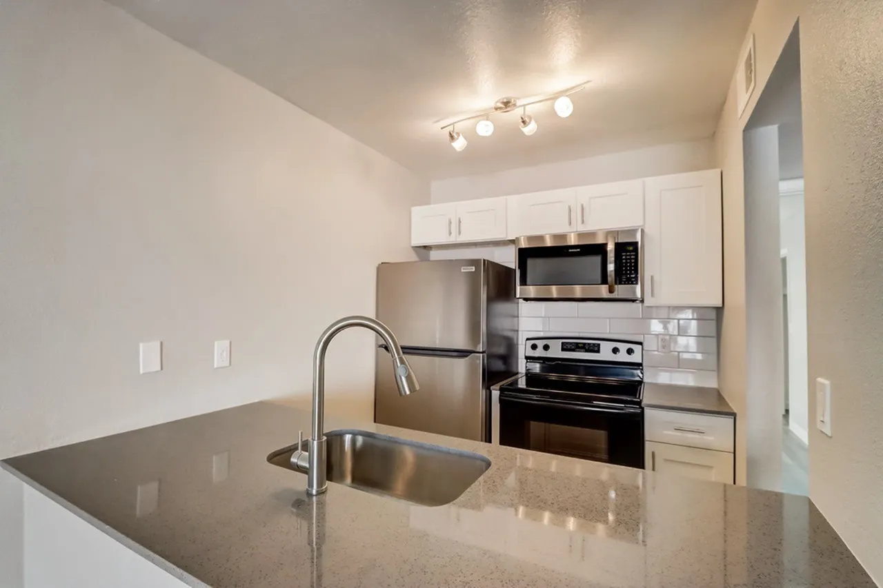 Kitchen, gray quartz countertops, white shaker cabinetry, stainless appliances, island sink