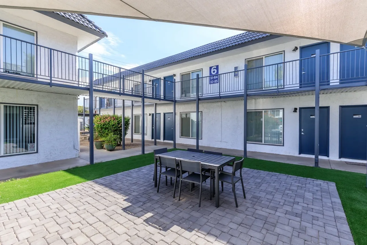 Courtyard with paved patio, dining table, synthetic turf, multi-level blue and white building