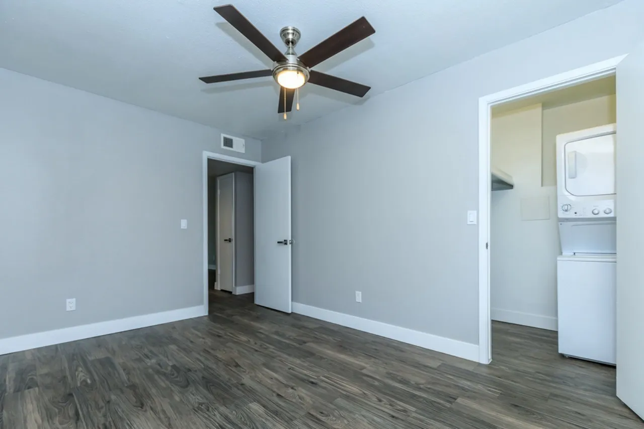 Bedroom, wood-style plank flooring, ceiling fan with light, stackable washer dryer