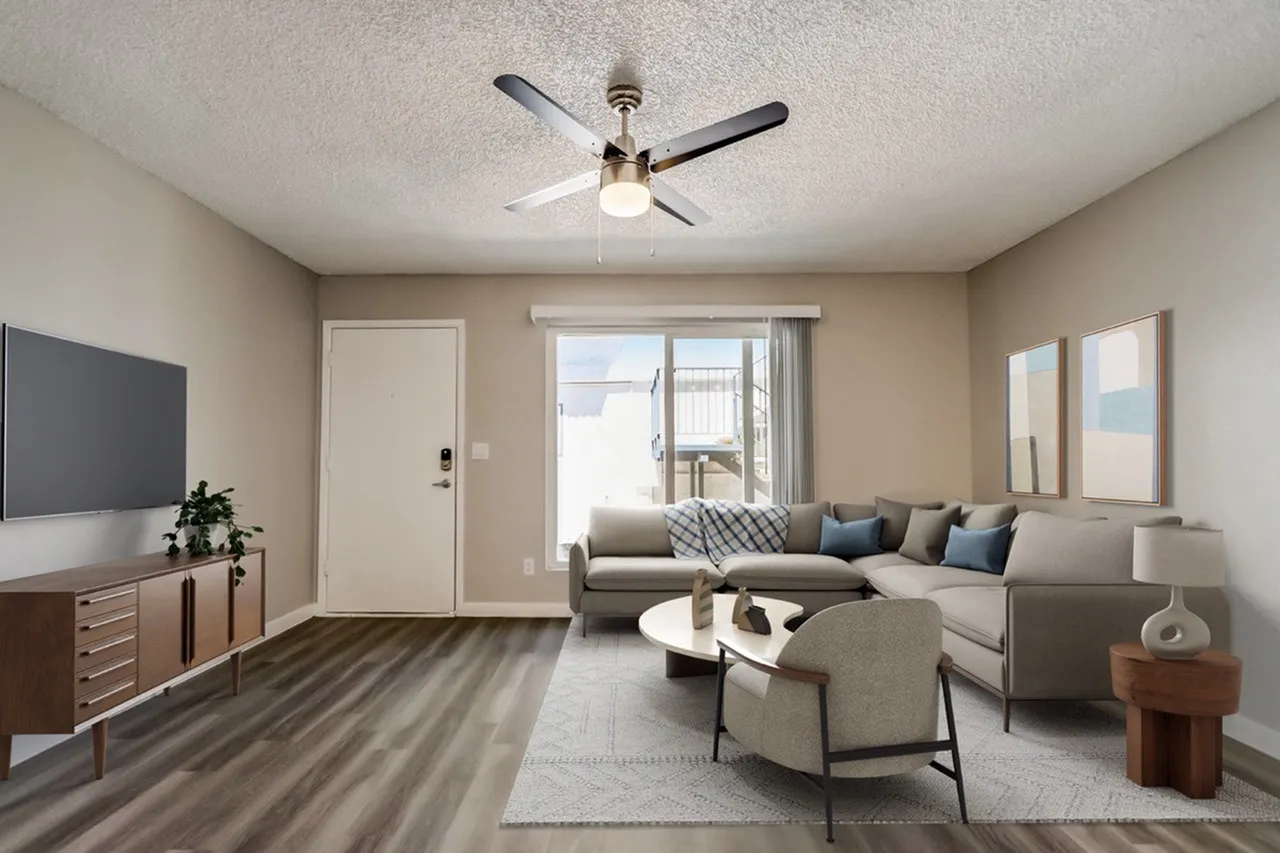Living room with wood-style plank flooring, ceiling fan, sofa seating, entry door