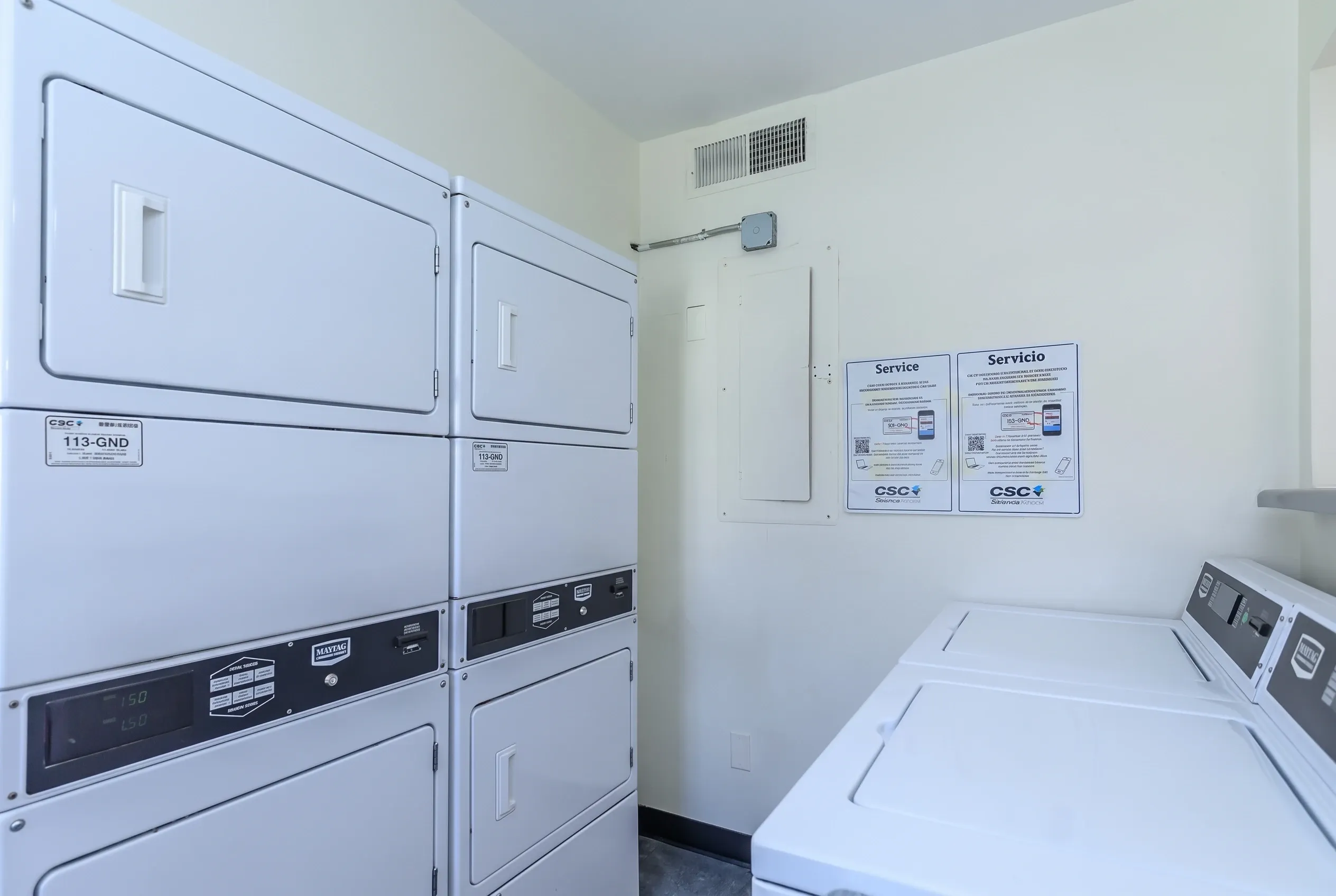 Laundry room, stackable dryers, white appliances, service signs
