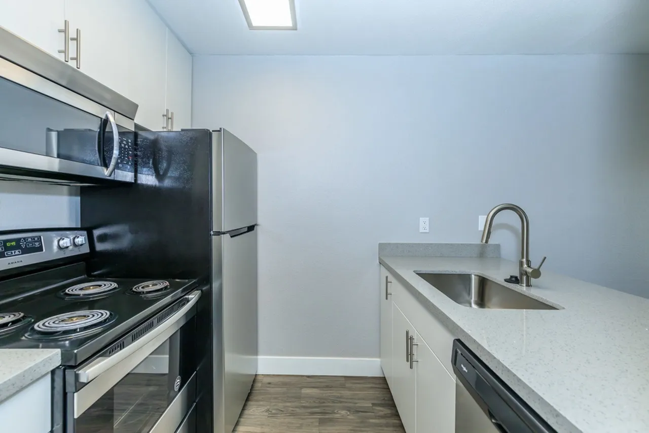Kitchen, black stainless appliances, white cabinetry, quartz countertops, wood-style plank flooring