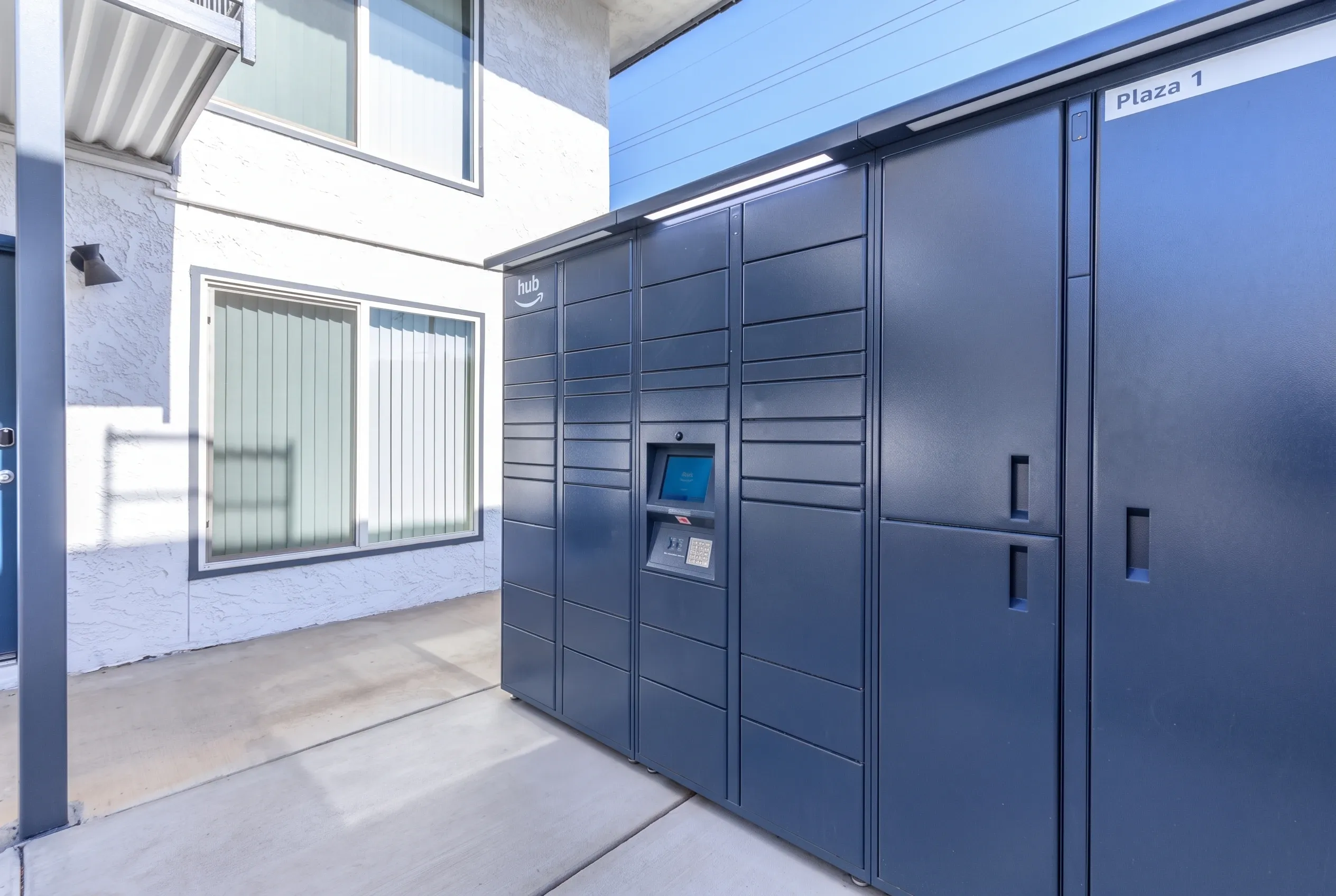 Entryway with dark gray modular package lockers, metal handles, digital access panel, polished concrete flooring