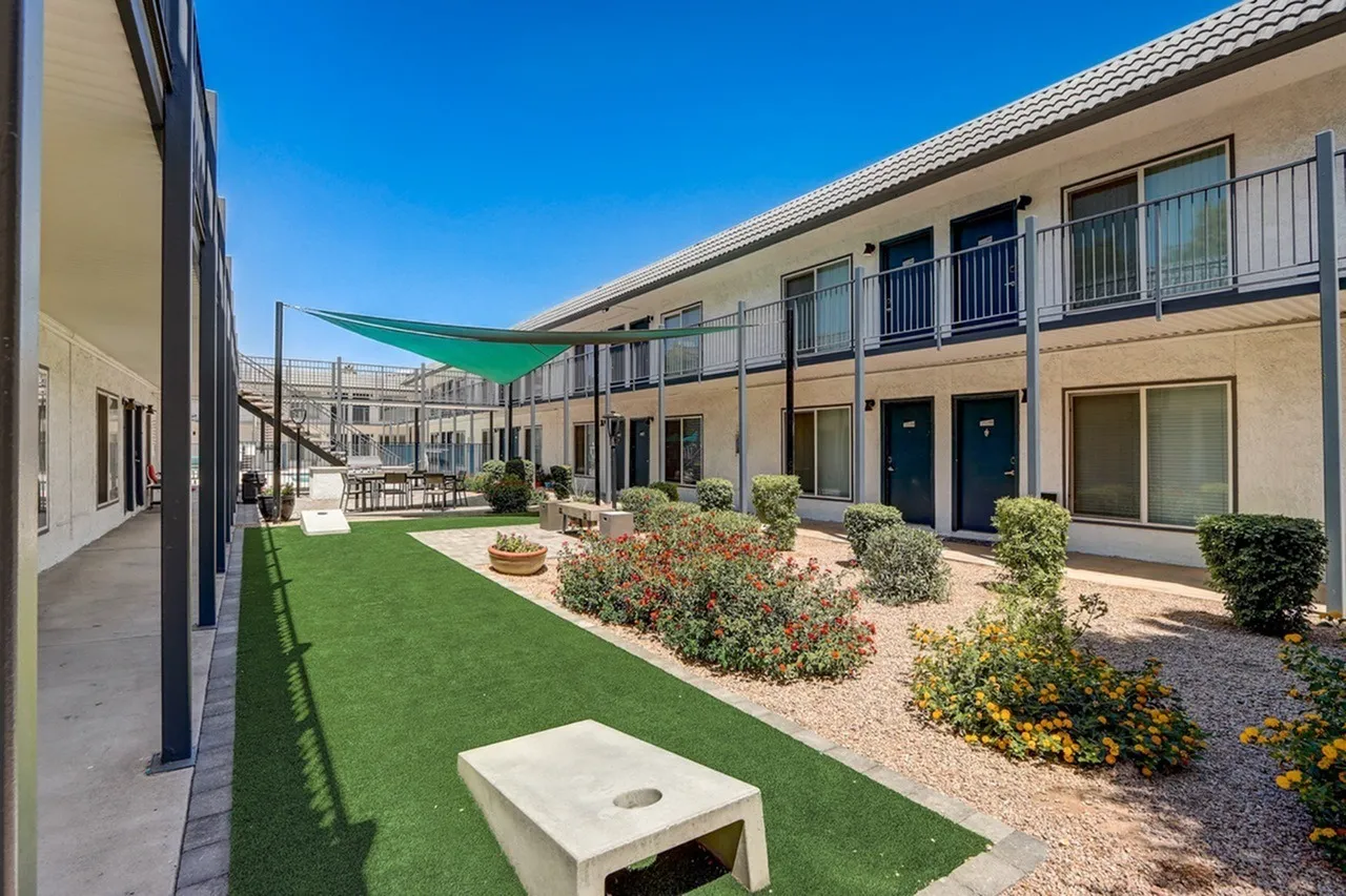Courtyard with synthetic turf, landscaping, shade structure, multi-story residential building