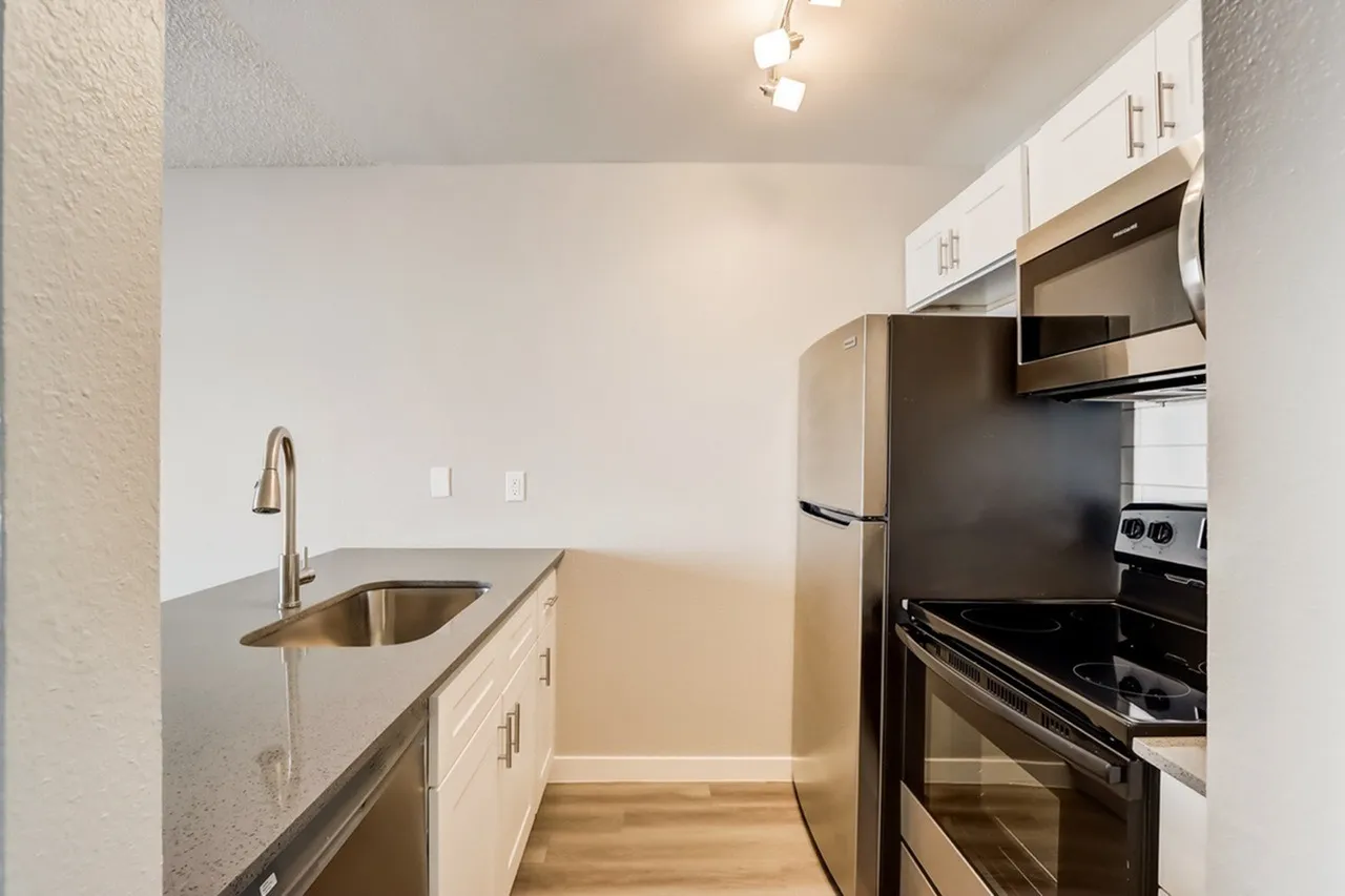 Kitchen, white shaker cabinetry, gray countertops, stainless steel appliances, wood-style plank flooring