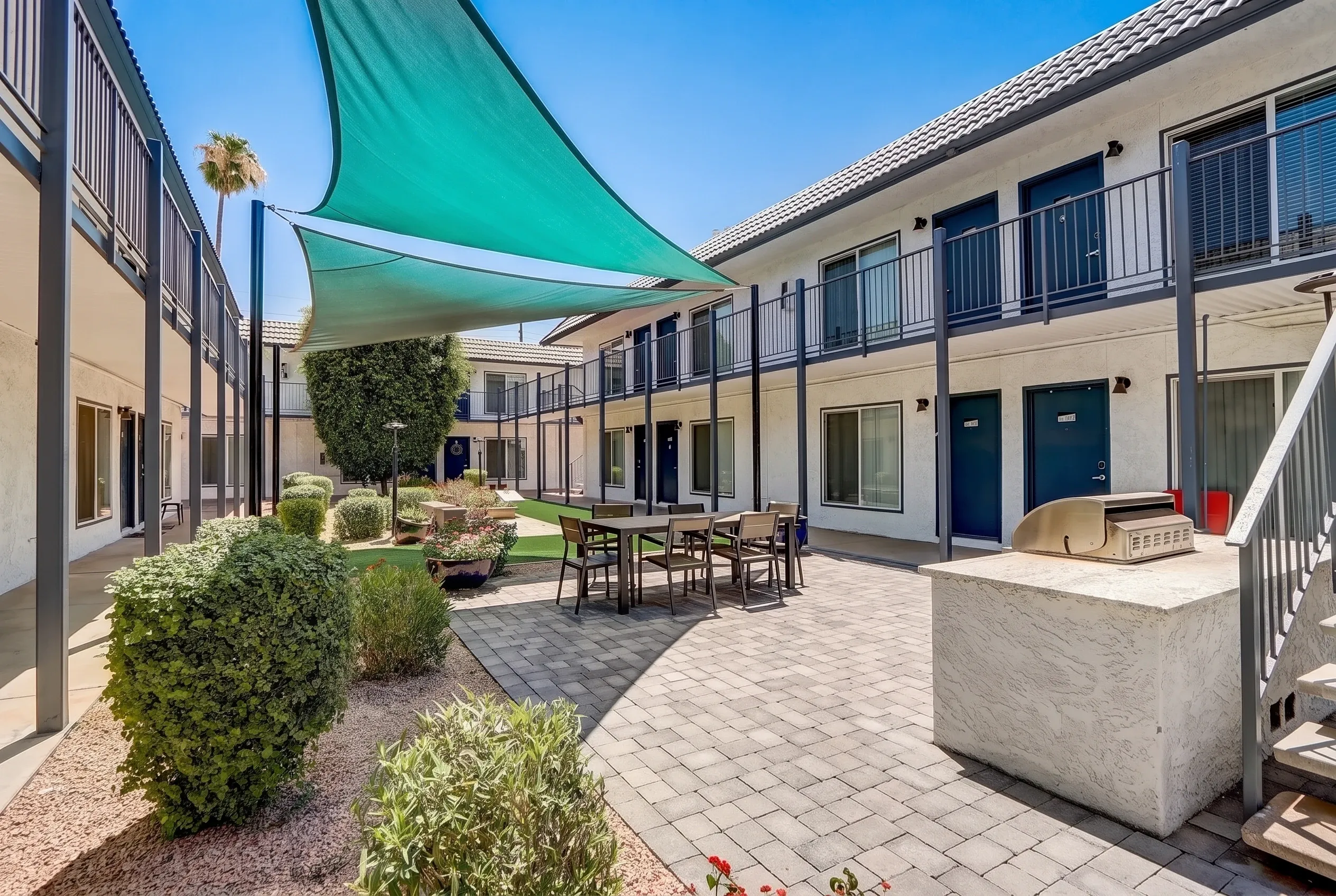 Courtyard with turquoise shade sails, paver flooring, furnished seating area, landscaping