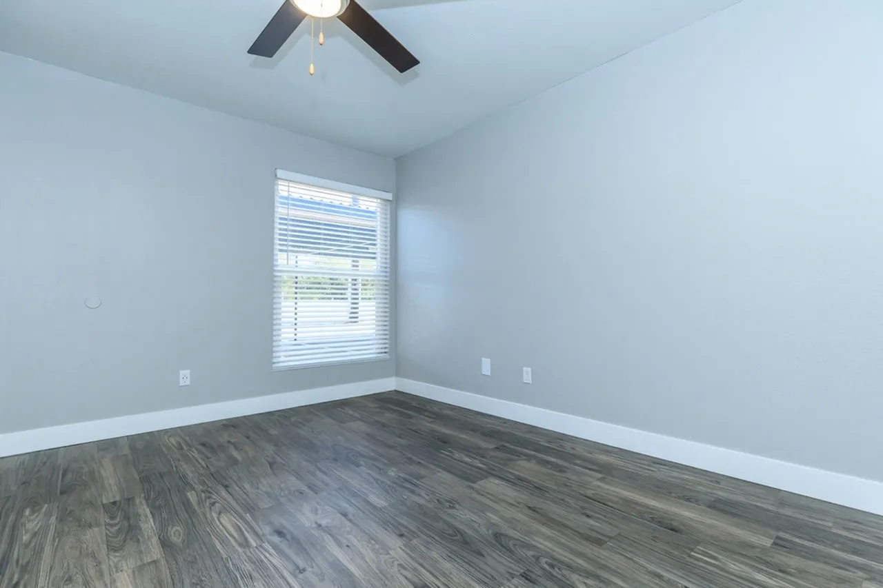 Bedroom, wood-style plank flooring, light blue walls, ceiling fan, window with blinds