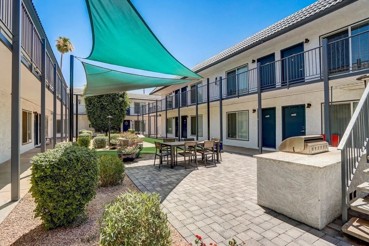 Courtyard with turquoise shade sails, paver flooring, furnished seating area, landscaping