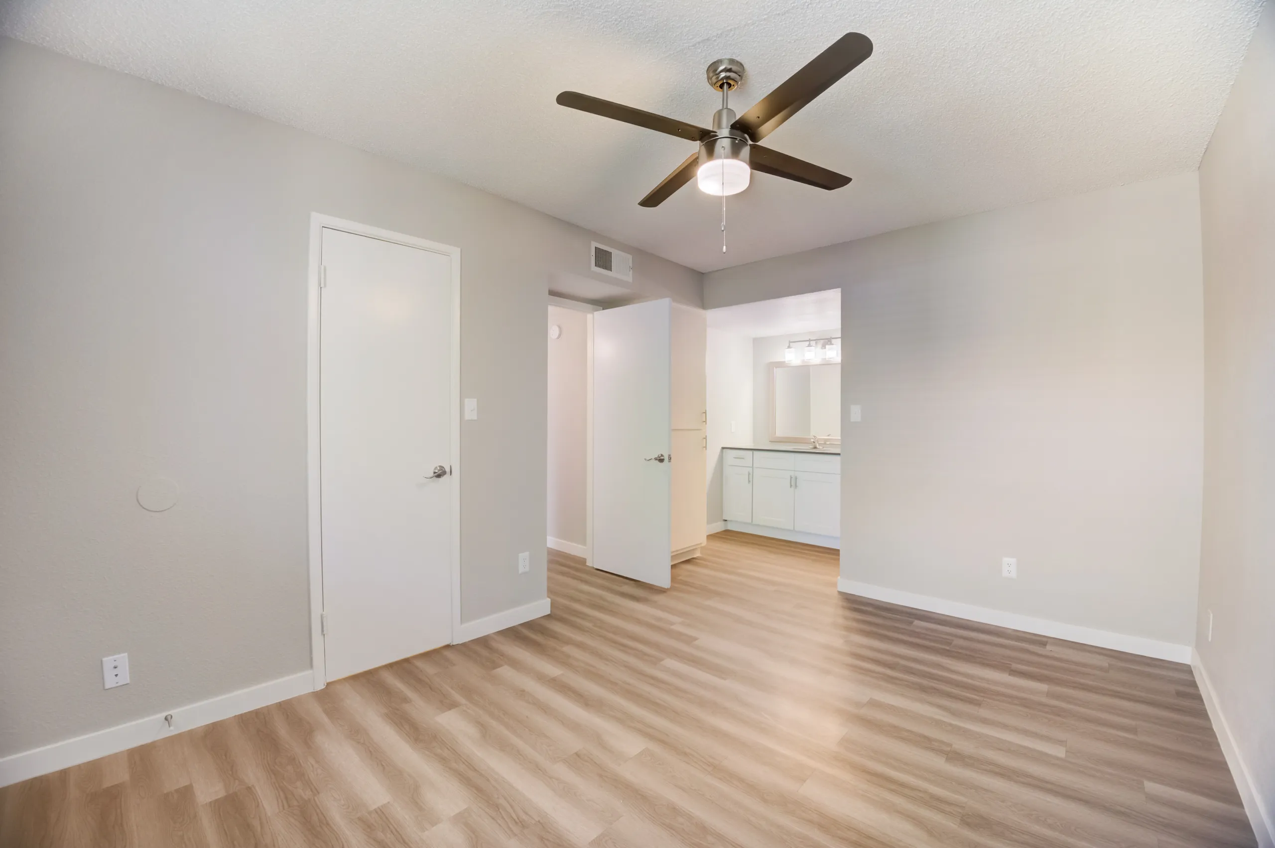 Primary bedroom with ceiling fan and view into ensuite bathroom