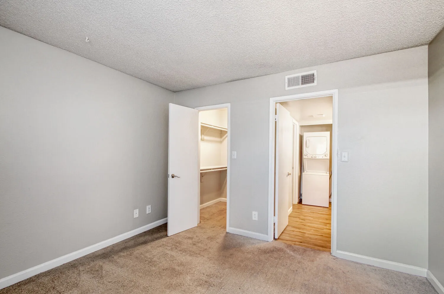Primary bedroom with view into walk-in closet and laundry area