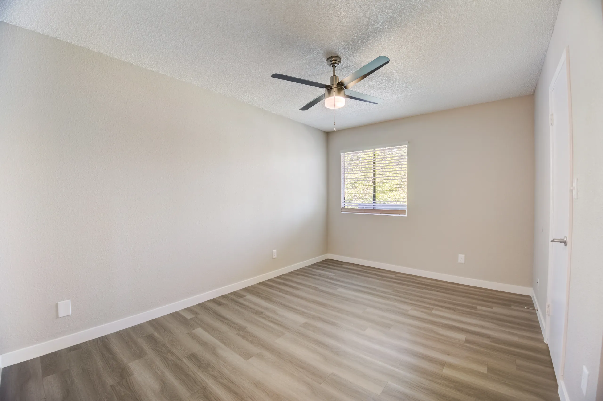 Primary bedroom with ceiling fan and wood-style plank flooring
