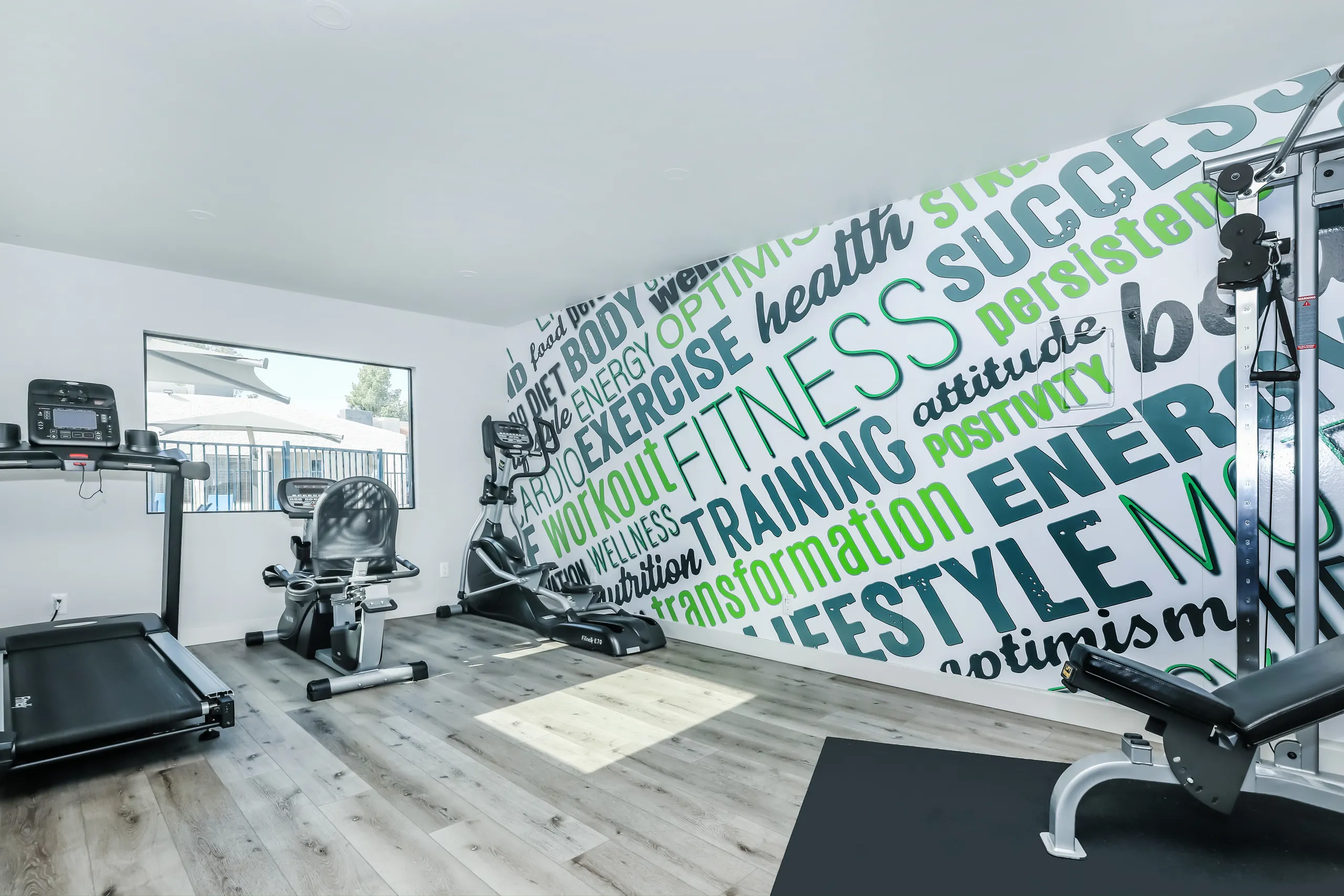 Apartment community fitness center with cardio equipment and motivational wall mural