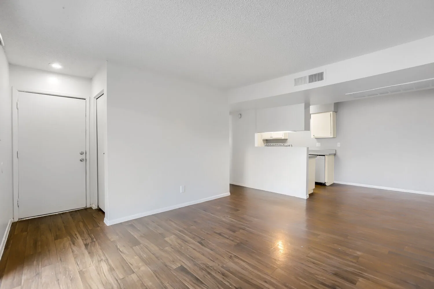 Living room with view into kitchen and entry door