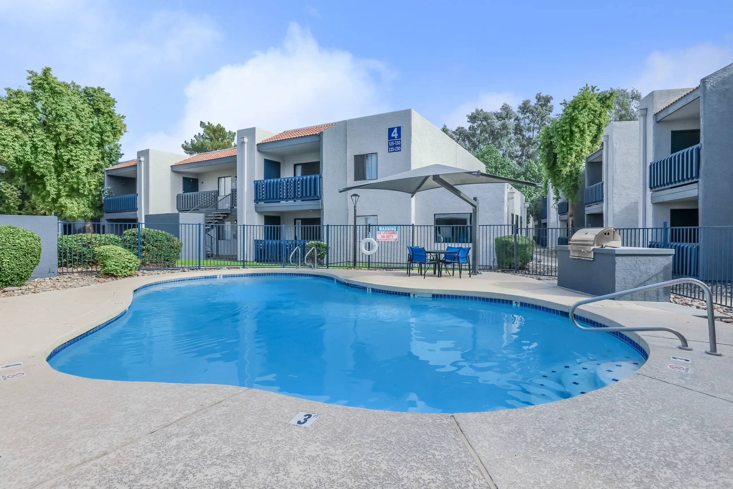 Community swimming pool with poolside seating and apartment buildings in the background