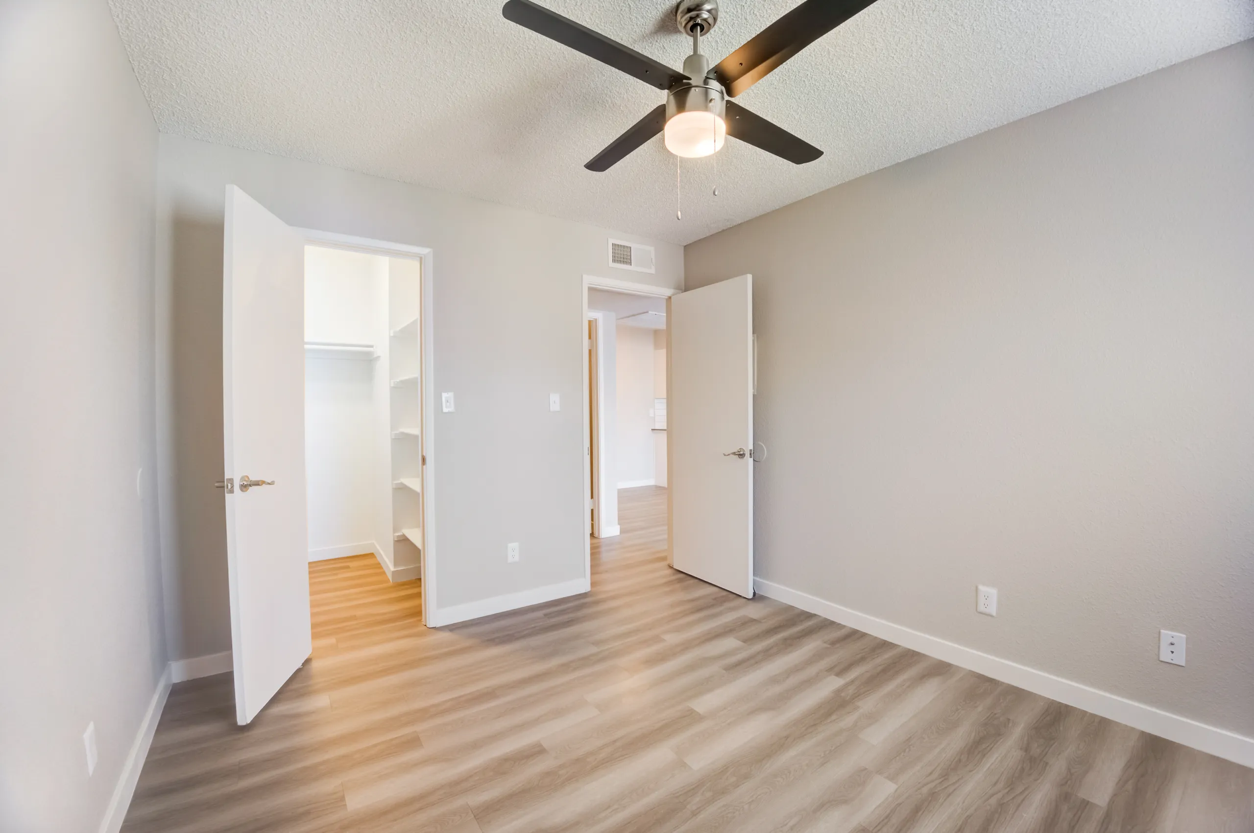 Bedroom with ceiling fan and view into walk-in closet