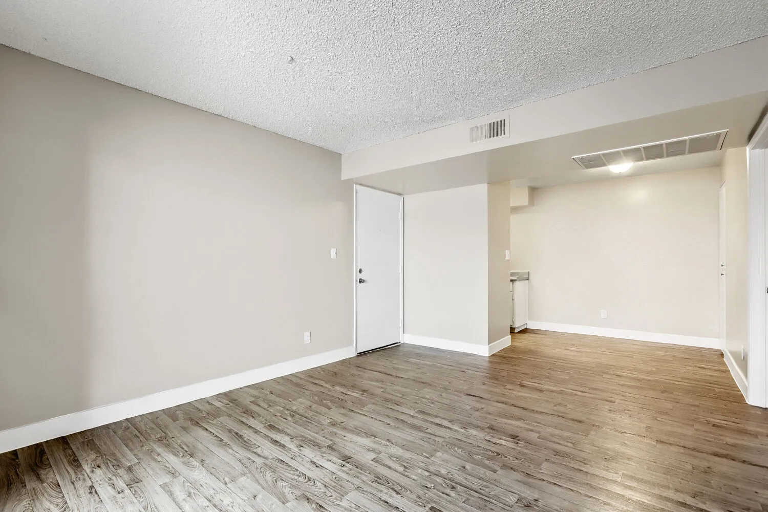 Living room with entry door and view into kitchen