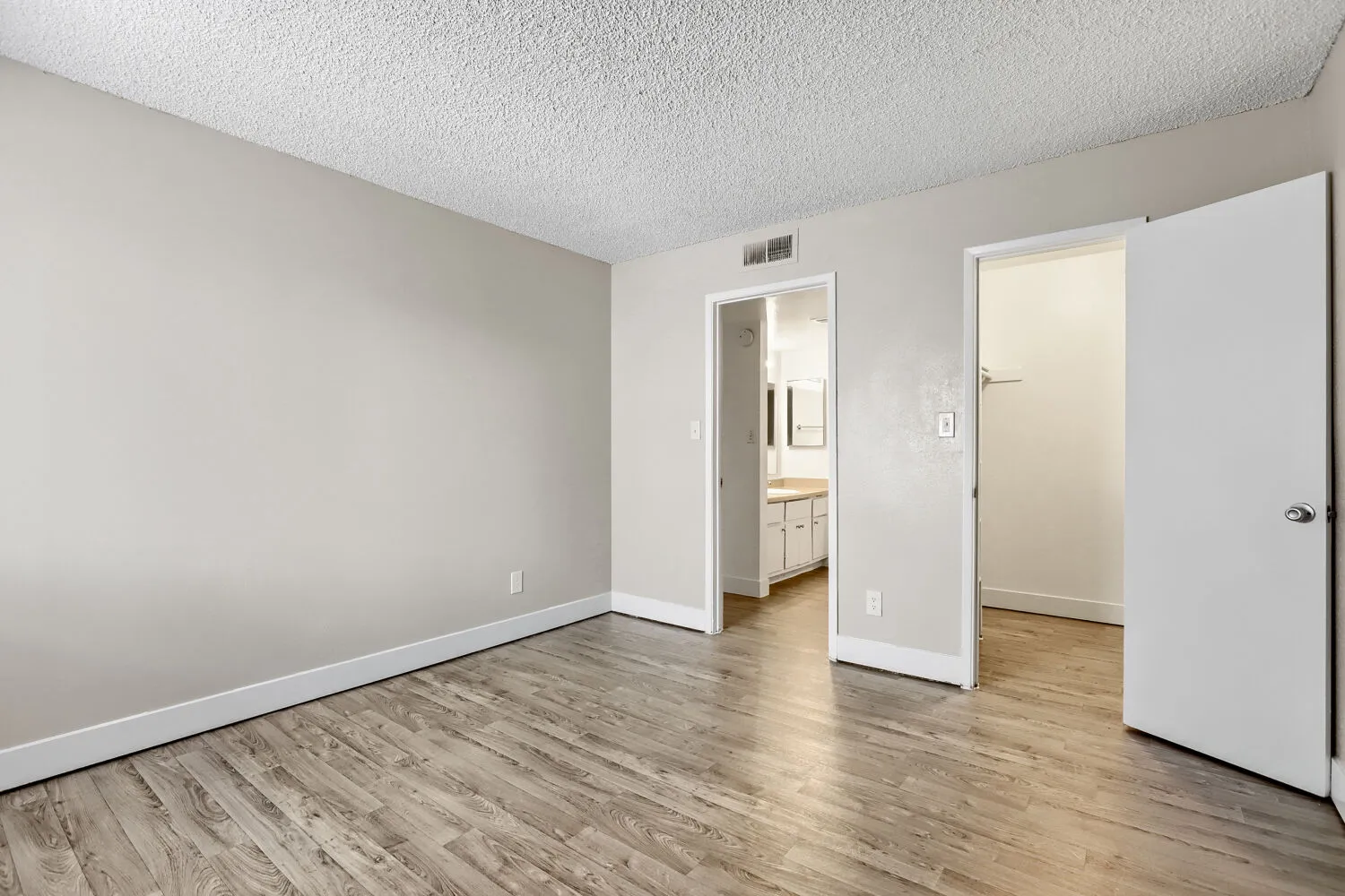 Primary bedroom with view into ensuite bathroom and walk-in closet
