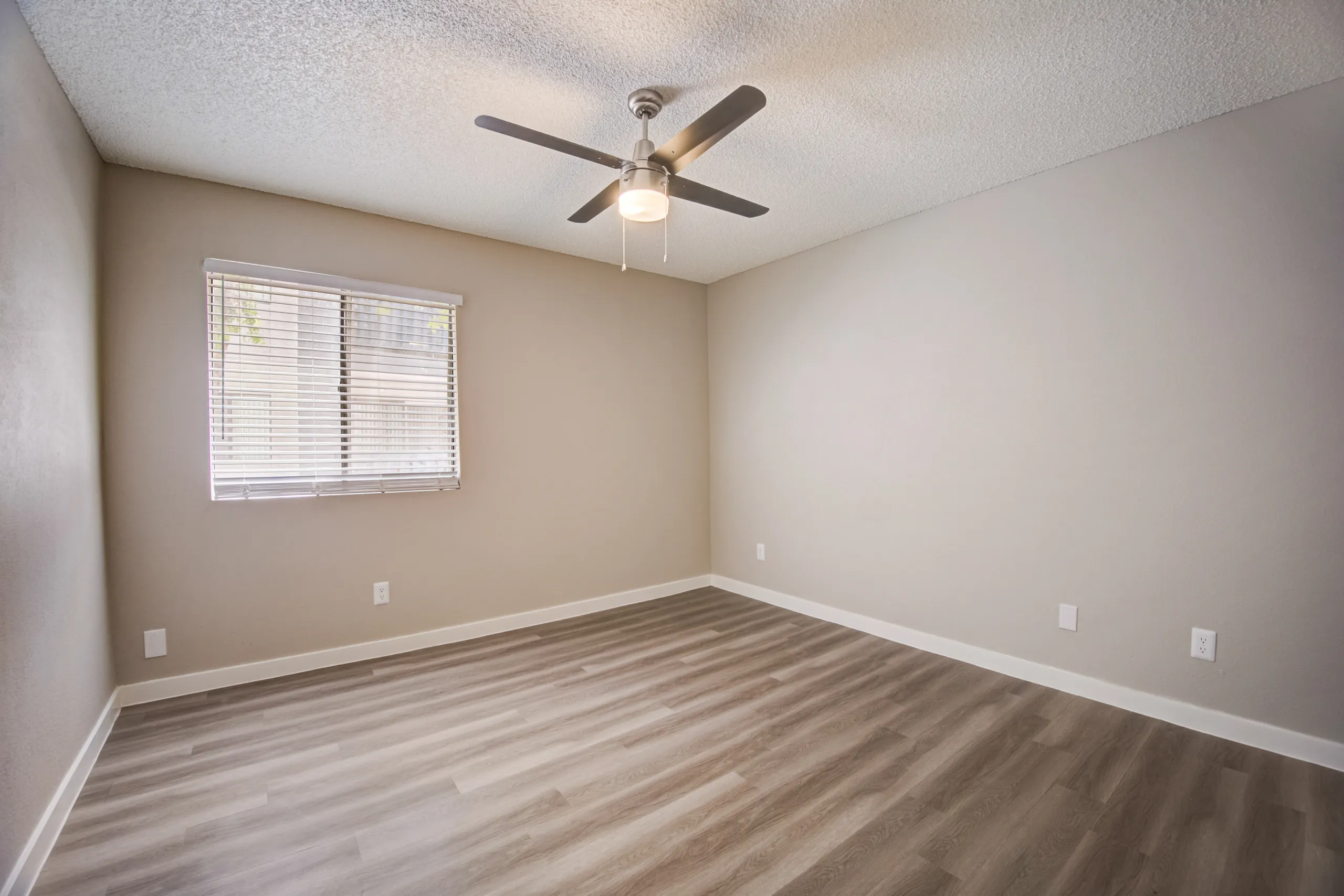Primary bedroom with ceiling fan and wood-style plank flooring