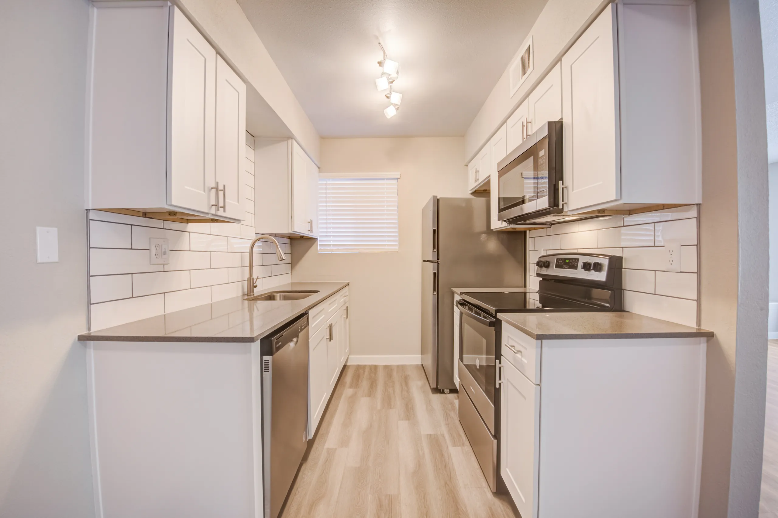 Kitchen with white cabinetry, stainless steel appliances, and subway tile backsplash