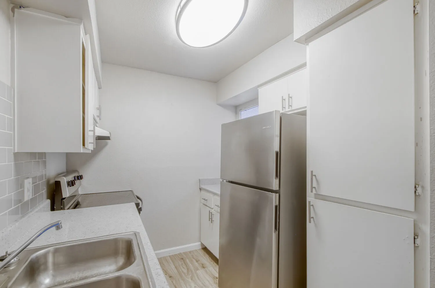 Kitchen with white cabinetry, stainless steel refrigerator, and tile backsplash