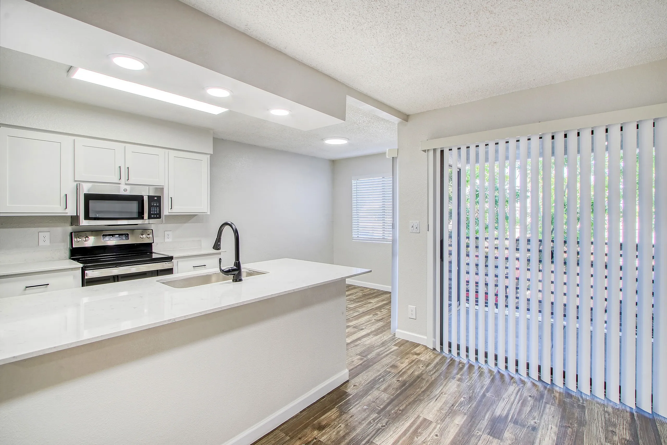 Kitchen, white shaker cabinetry, quartz countertops, stainless appliances, wood-style plank flooring