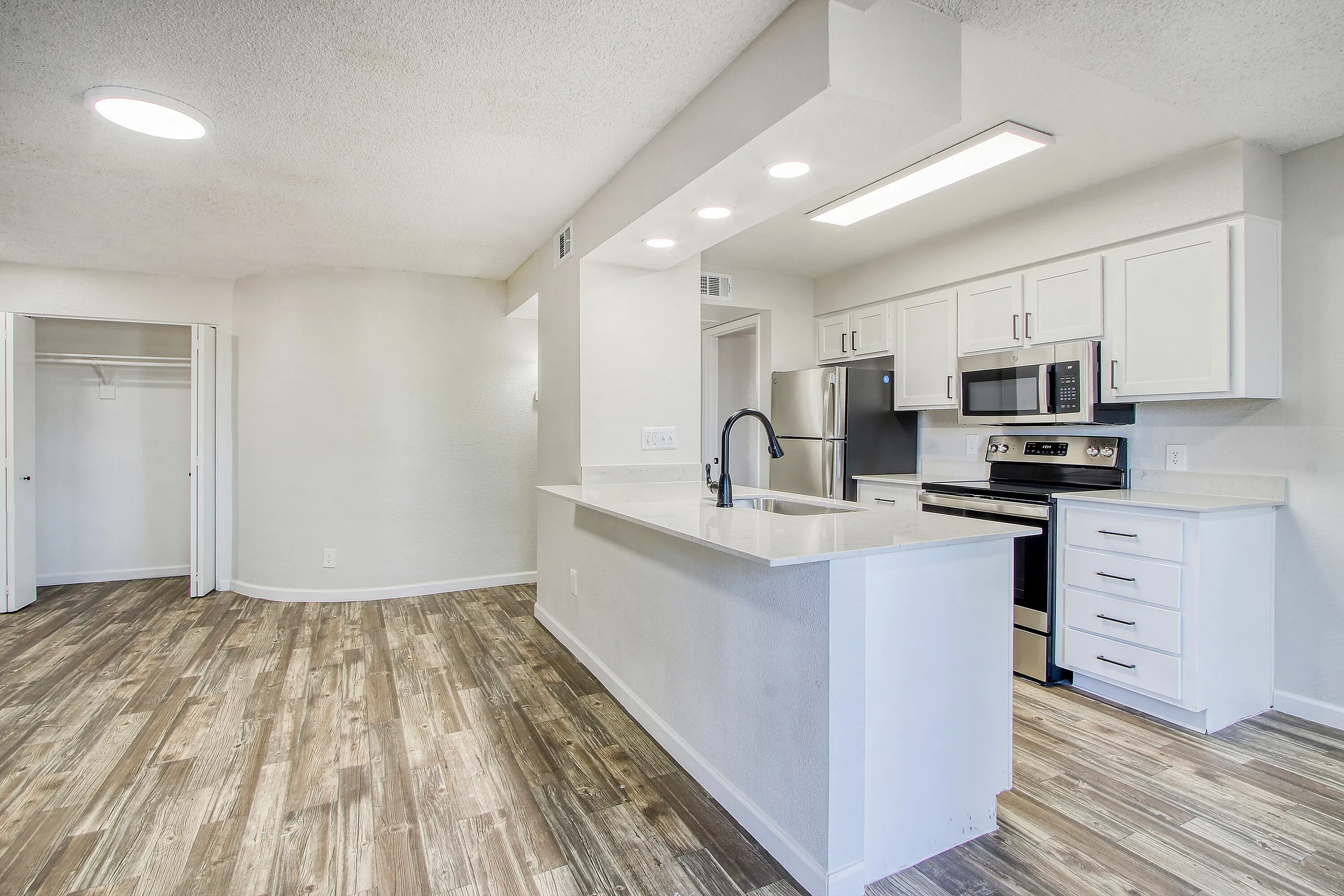Kitchen, white shaker cabinetry, quartz countertops, stainless appliances, wood-style plank flooring